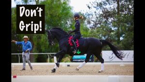 A woman in riding gear practices dressage at the canter on a black horse in an outdoor arena, while an instructor walks beside them. Text reads Don't Grip! with arrows highlighting posture and riding tips about not gripping with your legs.