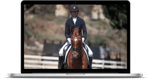 A person in equestrian attire rides a brown horse in an outdoor arena, featured on a laptop screen. The scene, part of a Blue Ribbon Course, has a blurred background with trees and fencing visible.