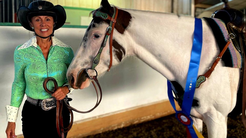 Strides member Cindy Kerr wearing Western competition clothing posing with her horse.