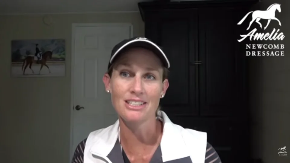A woman wearing a white vest and cap speaks indoors. Behind her is a dark cabinet, a white door, and a painting of a horse and rider. The top right shows the Amelia Newcomb Dressage logo, reflecting her passion for Dressage lessons.